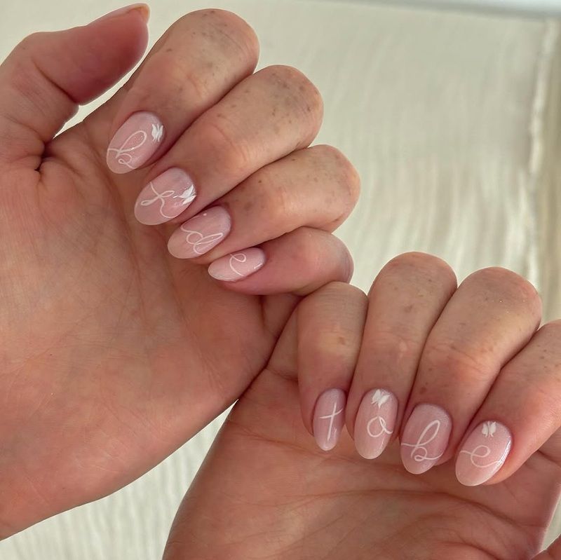 Two hands showing manicured nails with a light pink polish and designs.