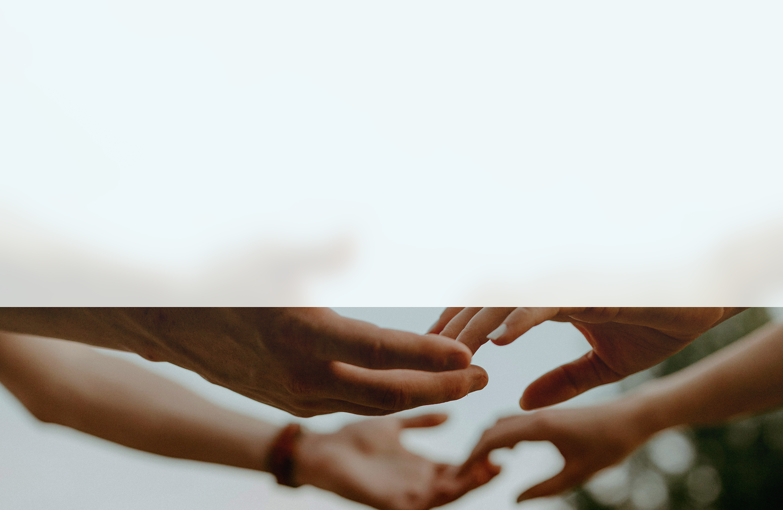 Hands reaching out to each other against a soft, blurred background.