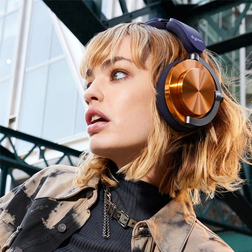 Woman with short hair wearing large headphones, looking away in an urban setting.