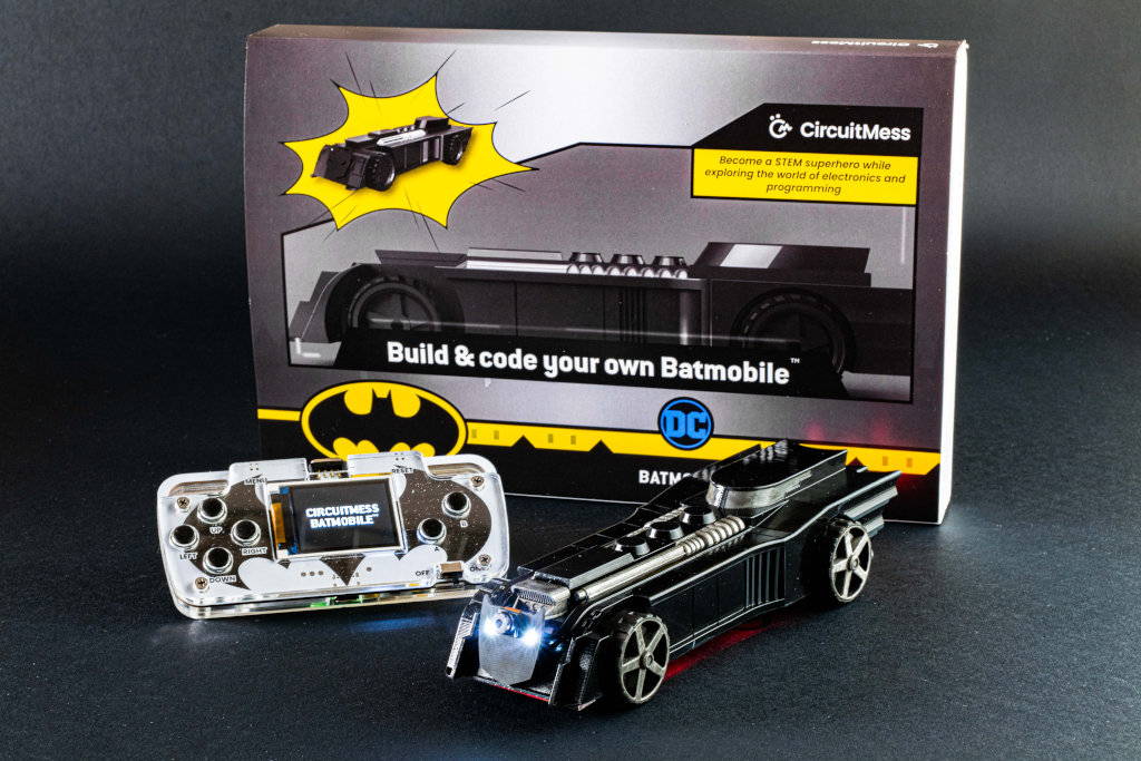 The CircuitMess Batmobile STEM kit fully assembled, next to its box, and controller.