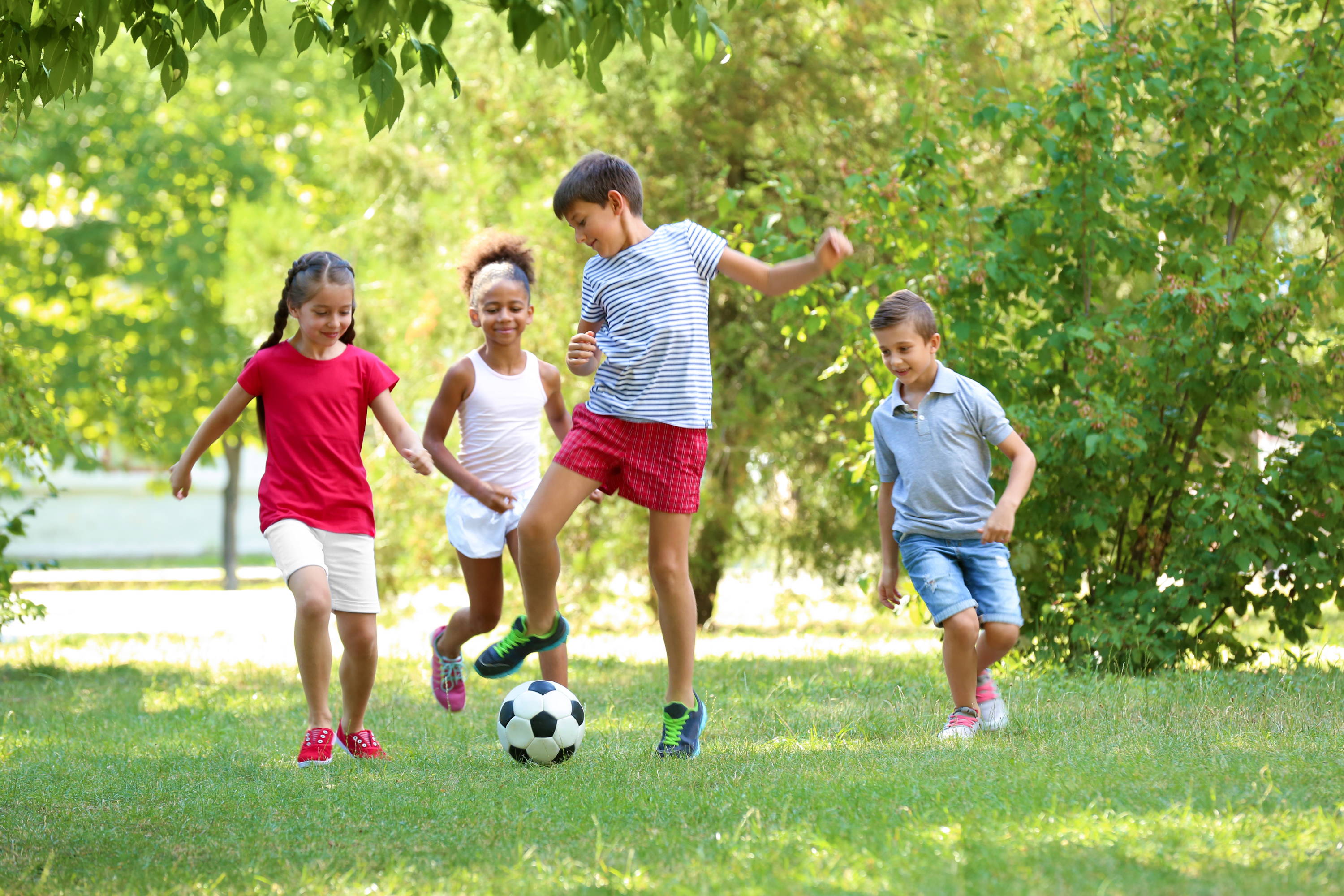 Kids playing soccer while outdoors