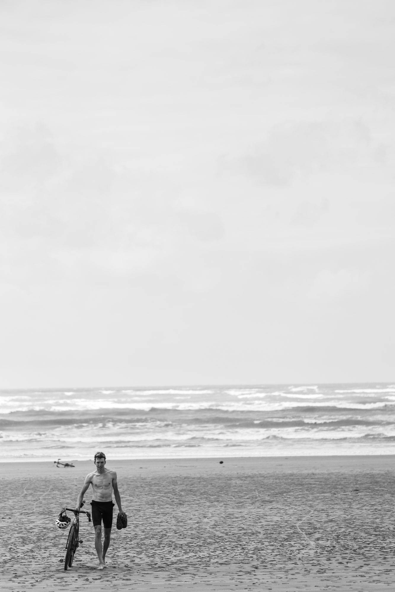 Marin walking his bike on a sandy beach with his bike