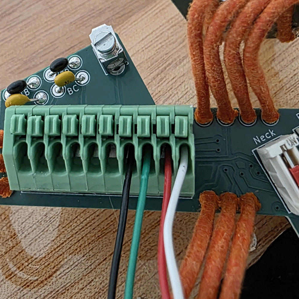 Close-up of a circuit board with wires connected to a terminal block.