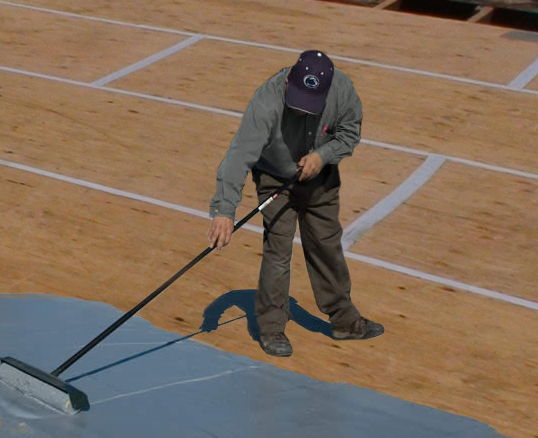 Person painting a surface with a roller on a construction site.