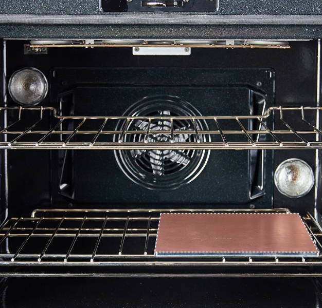 An oven interior with two racks. The lower rack has single Misen Oven Steel covering only the right side of the rack.