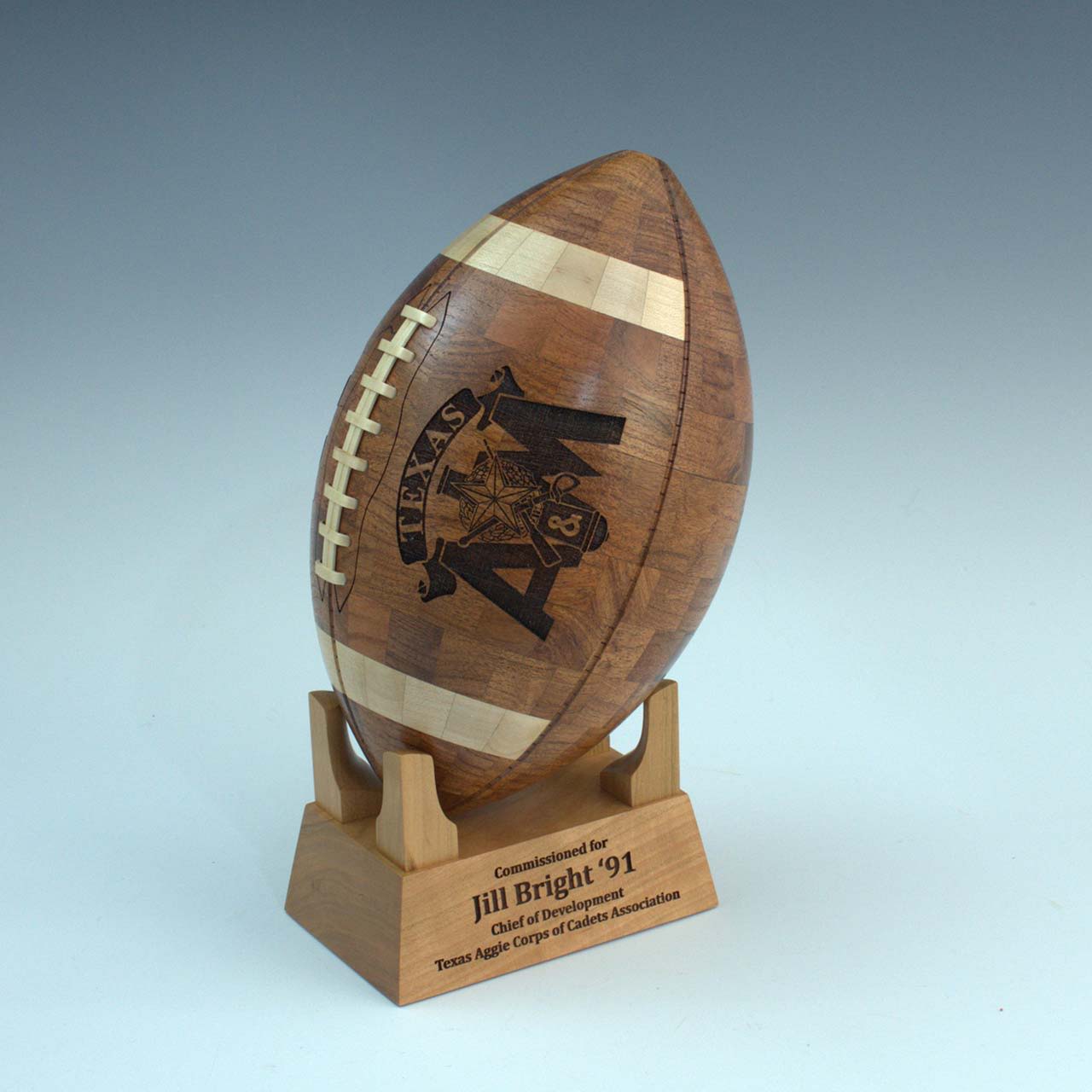Wooden trophy football on a stand with engraved text.