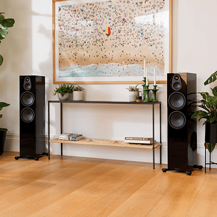 Two tall black speakers beside a shelf in a modern living room.