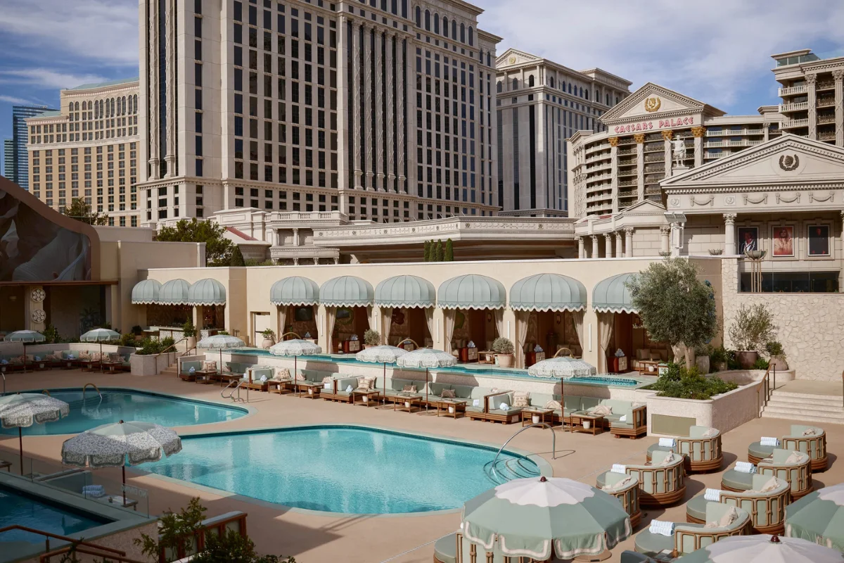 Las Vegas luxury hotel pool deck with commercial lounge chairs, umbrellas, and outdoor seating surrounding multiple pools