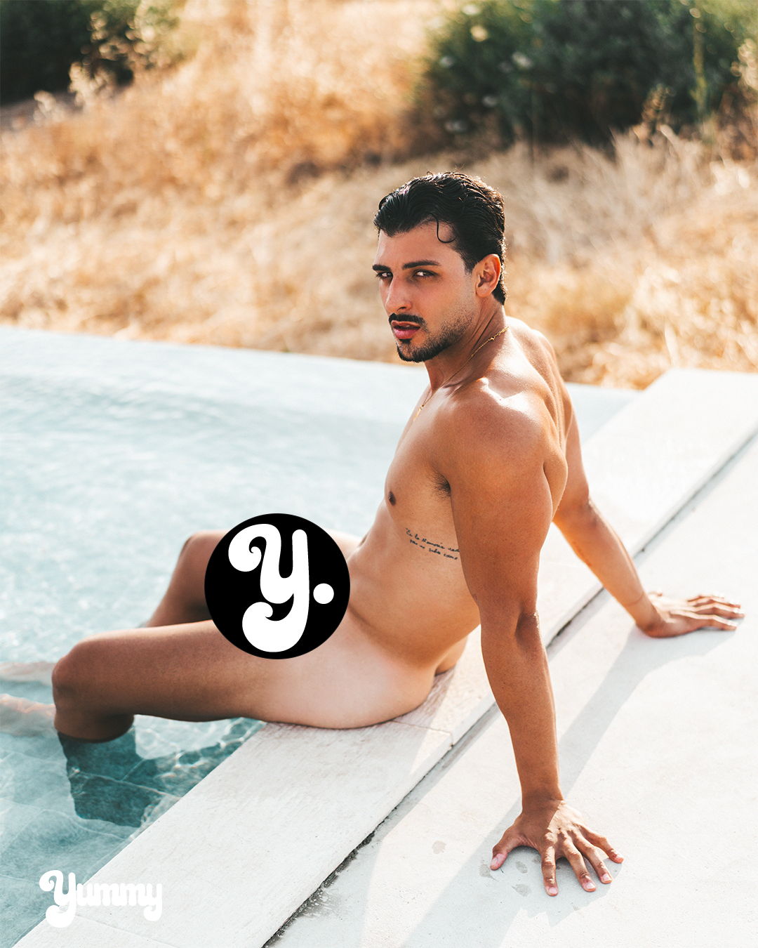 A man sitting by a pool in a natural setting.