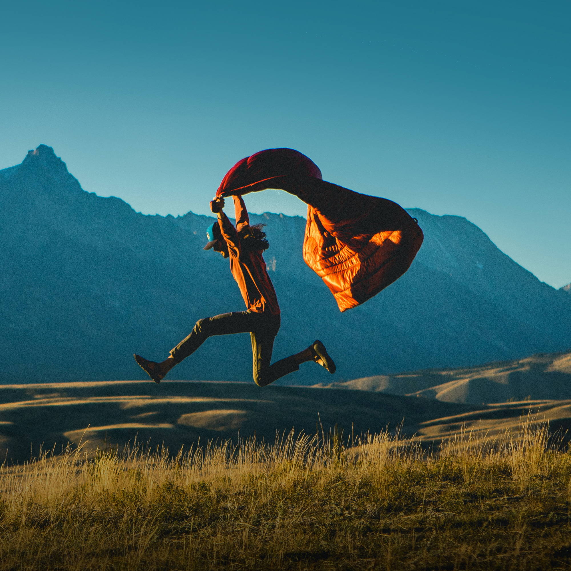 Man running through the wild with an orange Rumpl blanket