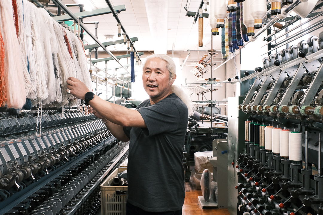 Person working in a textile factory surrounded by machines and materials.
