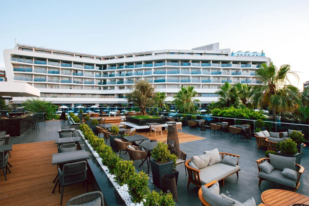 Luxury resort rooftop terrace with multiple outdoor furniture zones, poolside seating, dining areas, and lounge spaces