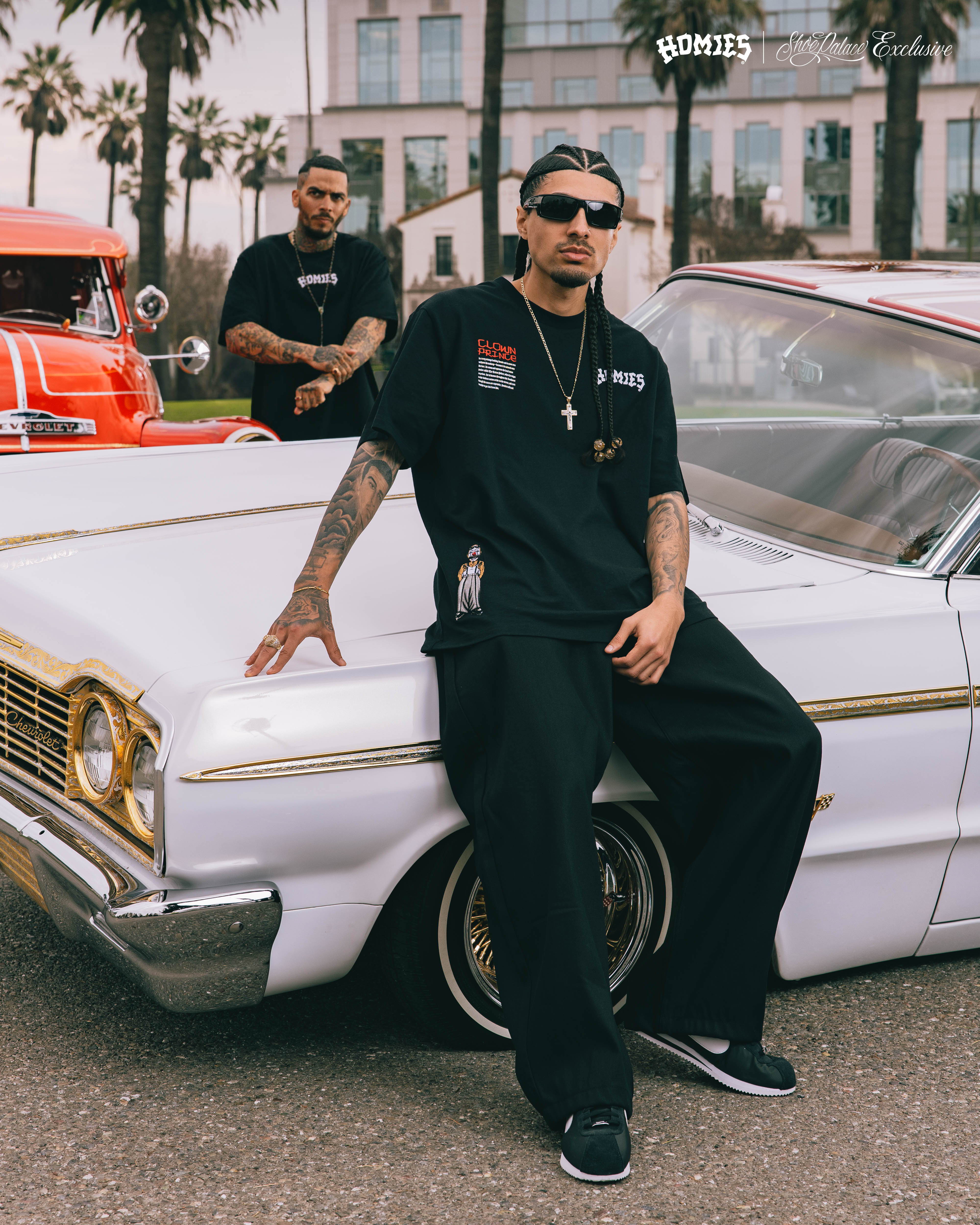 Two men posing with a classic car at an outdoor event.