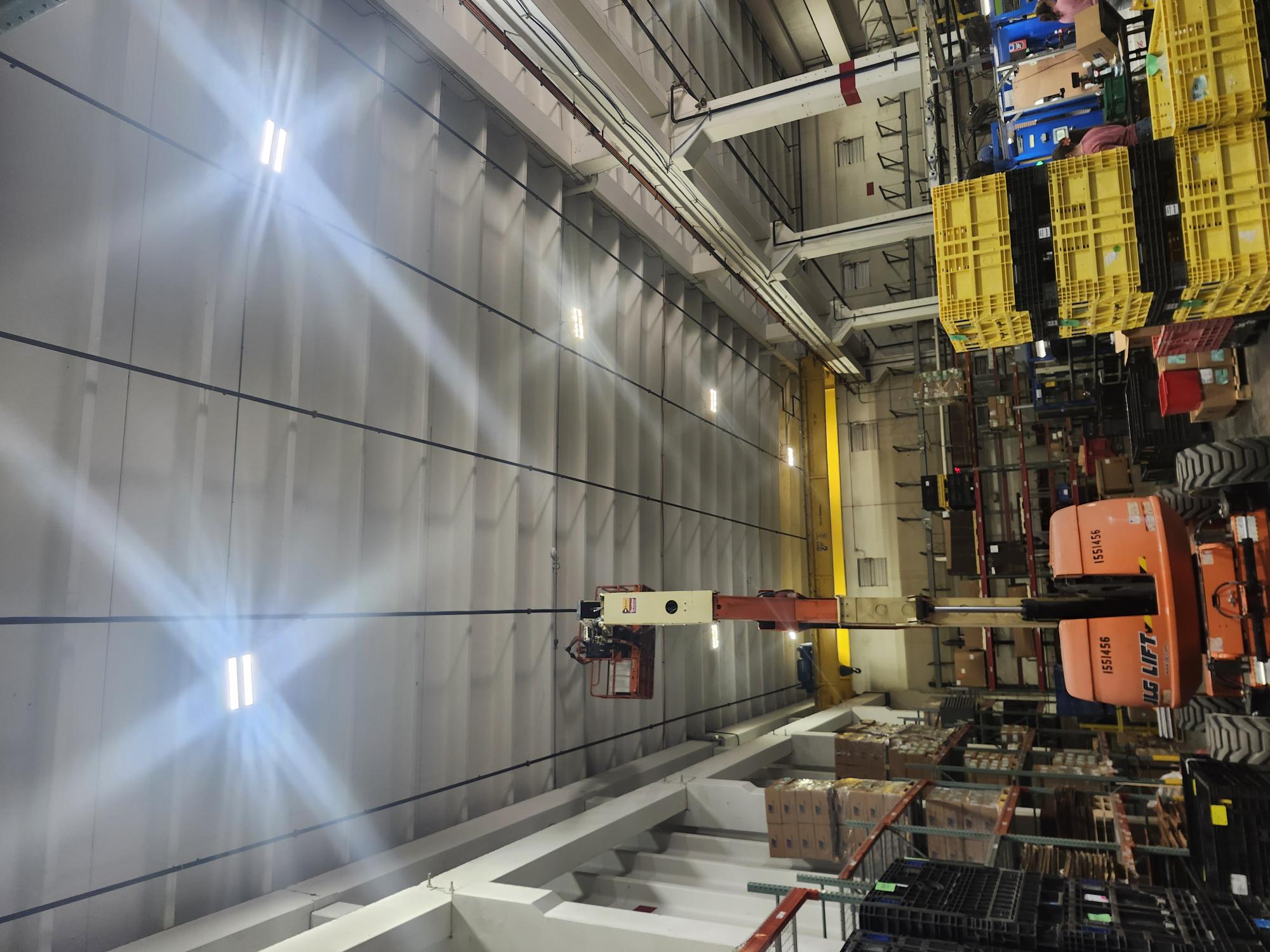 Warehouse interior with a lift, shelves, and stacked boxes.