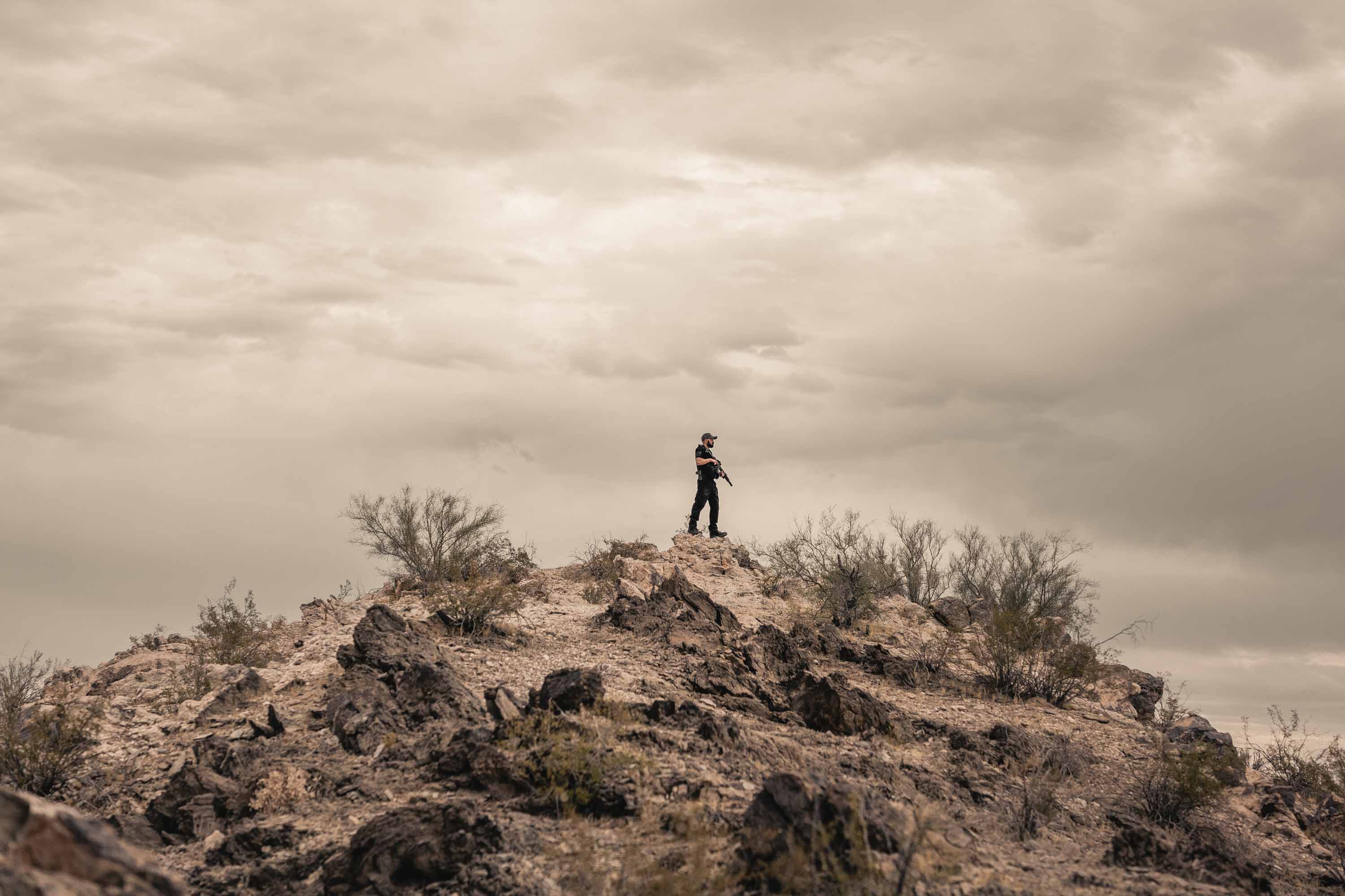 Man Standing on Mountain with a Gun