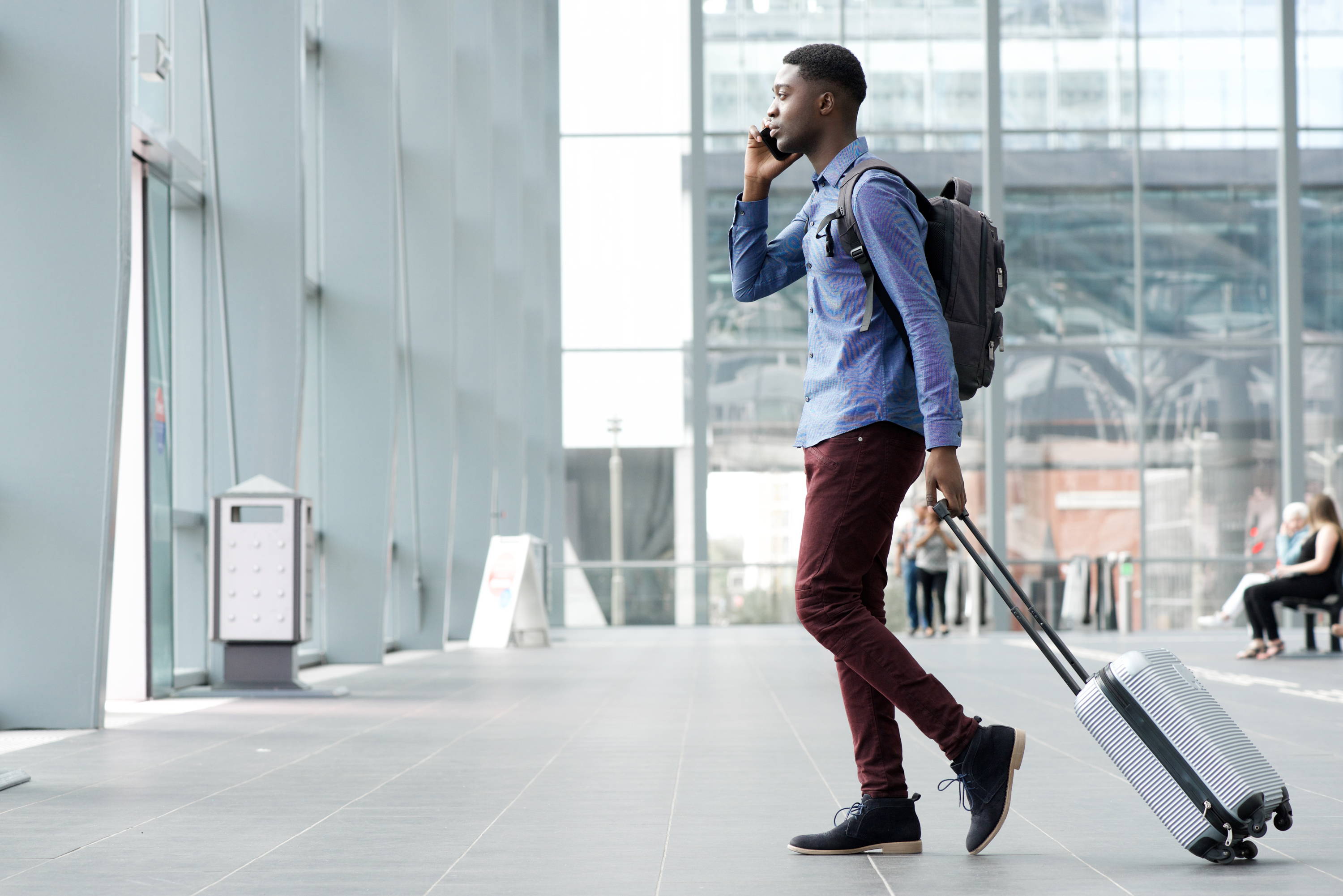 Man traveling with backpack and suitcase while on the phone