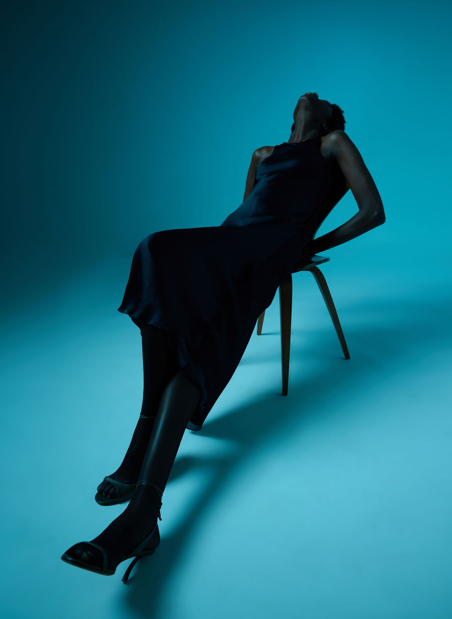Silhouette of a woman in a dress reclining on a chair.
