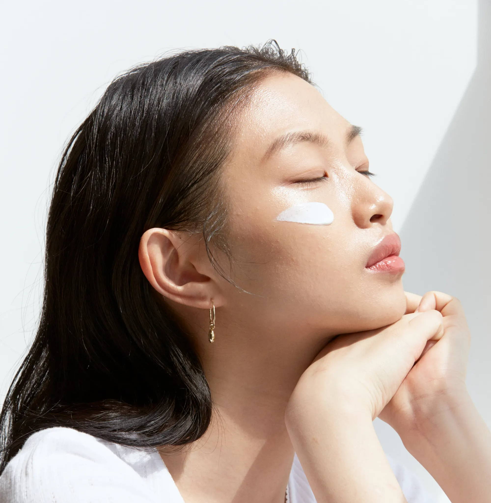 Girl with streak of sunscreen on her cheek, leaning on her hands with eyes closed