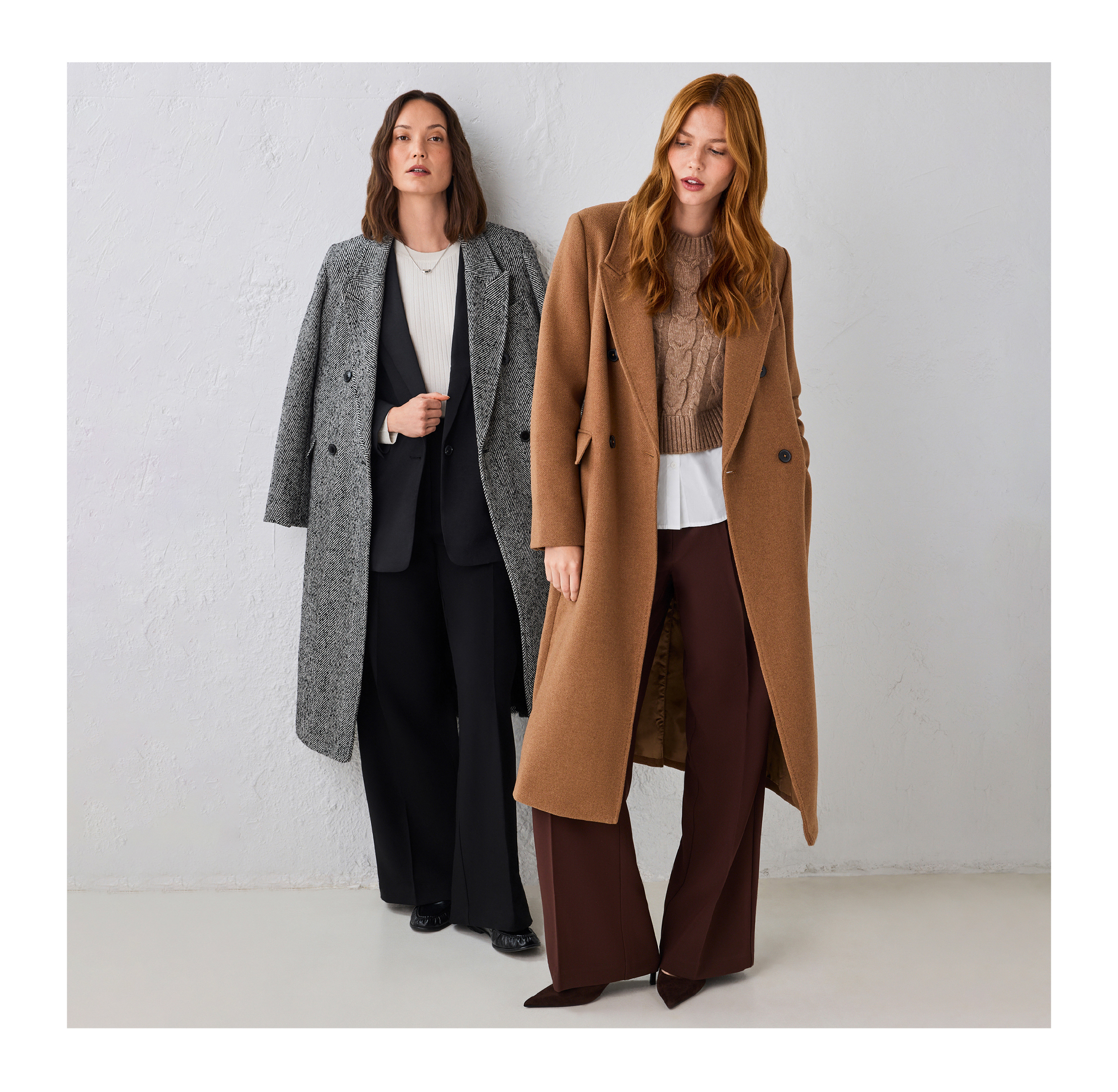 Two women wearing stylish coats standing against a light background.