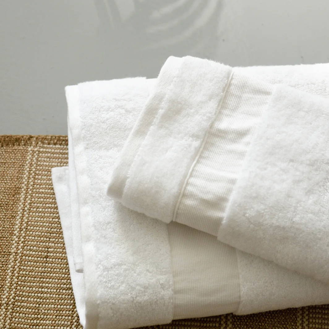 a white hand towel neatly stacked on a white bath towel