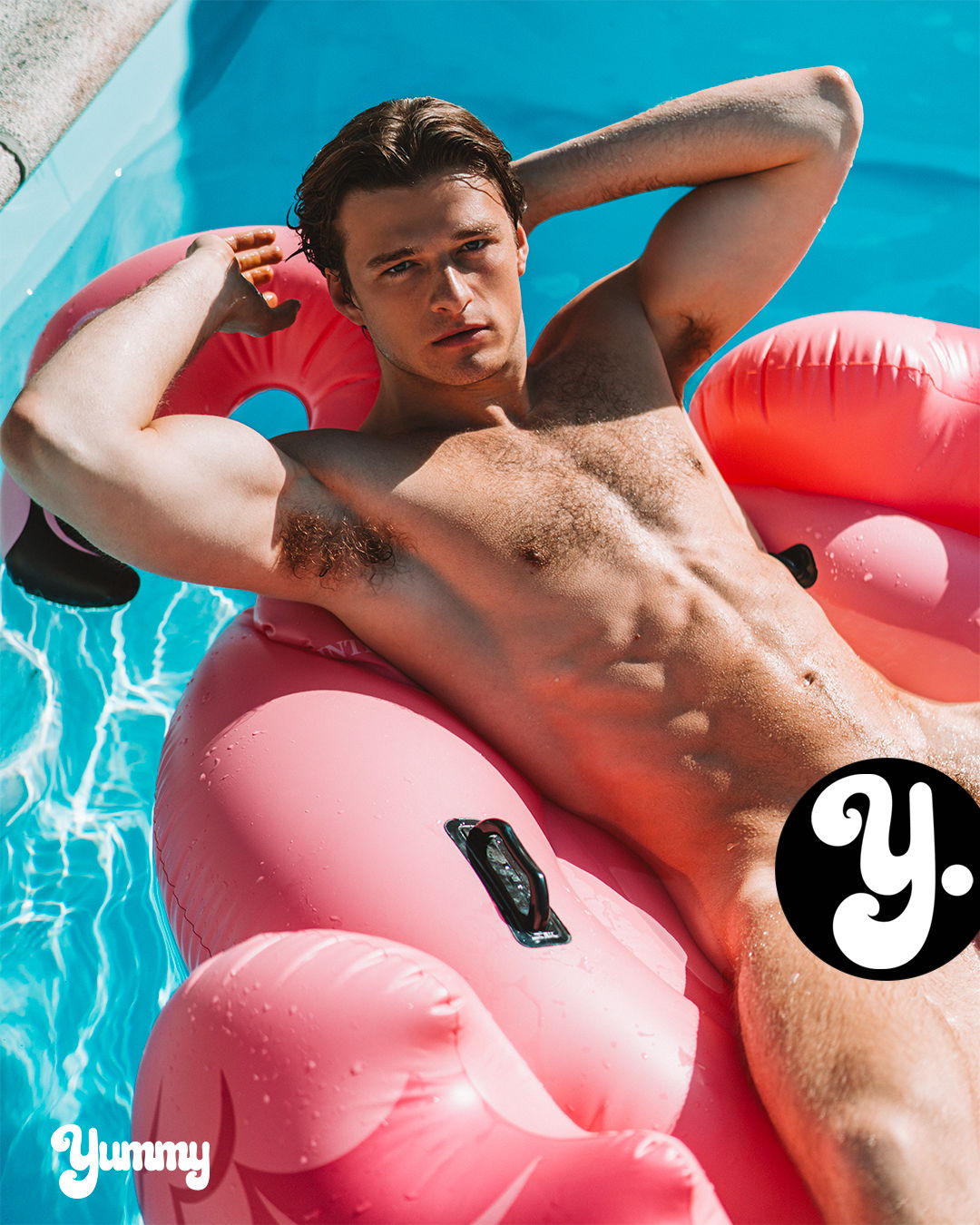 Young man lounging on a pink float in a swimming pool.