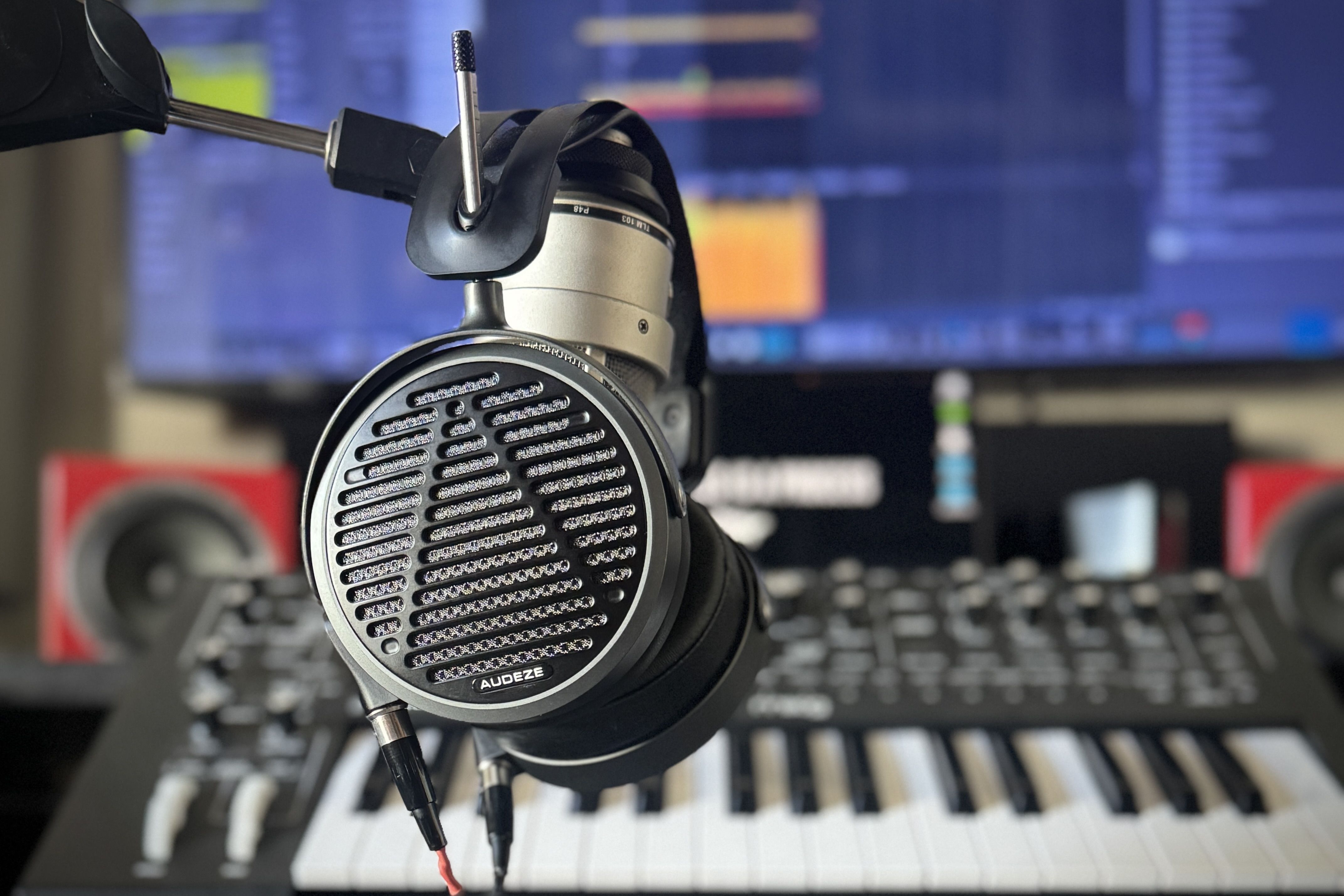 Audeze MM-500 headphones on a microphone in front of a piano and monitor 