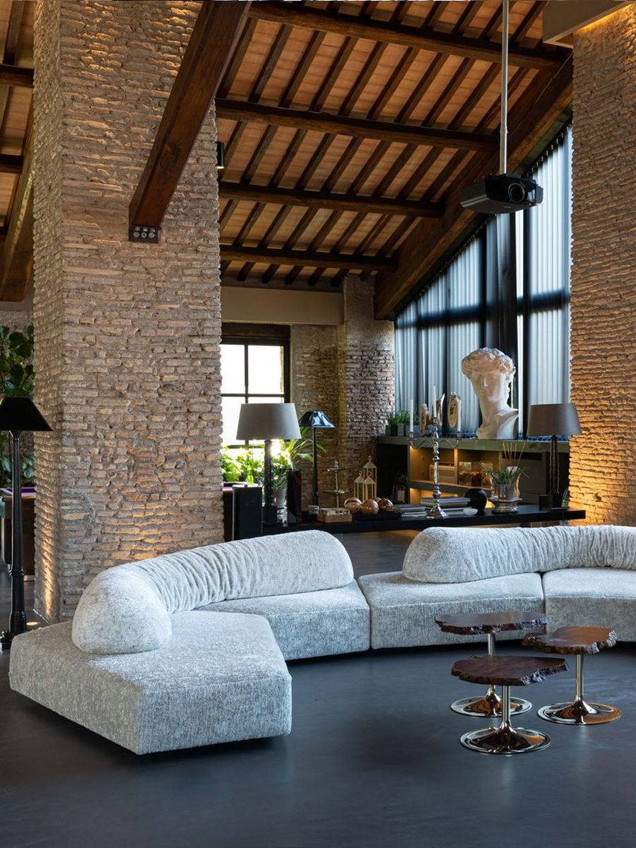 Modern living room with a curved sofa and stone walls.