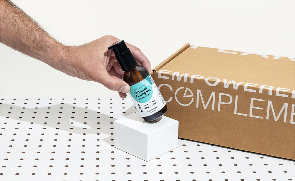 Hand holding Complement Omega Complex bottle.