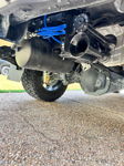 Low-angle rear passenger side view of black air tank and train horns with blue plumbing near rear axle
