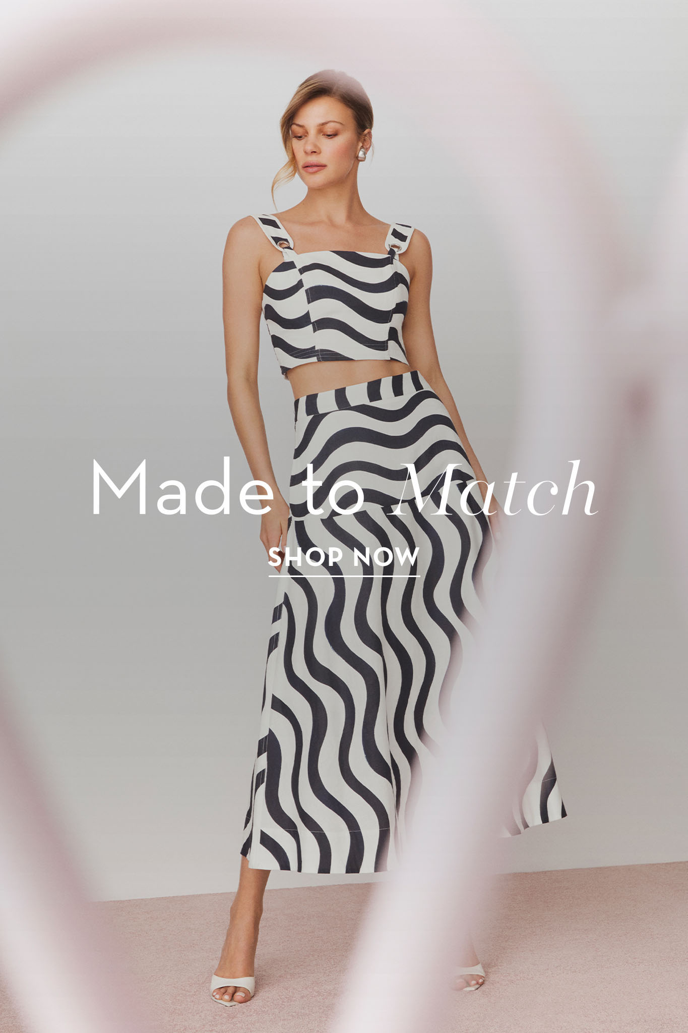 Woman in a black and white wavy-patterned outfit, promoting a clothing line.