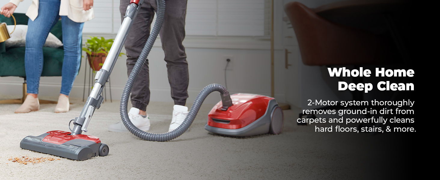 Person vacuuming a carpet with a red vacuum cleaner in a living room.