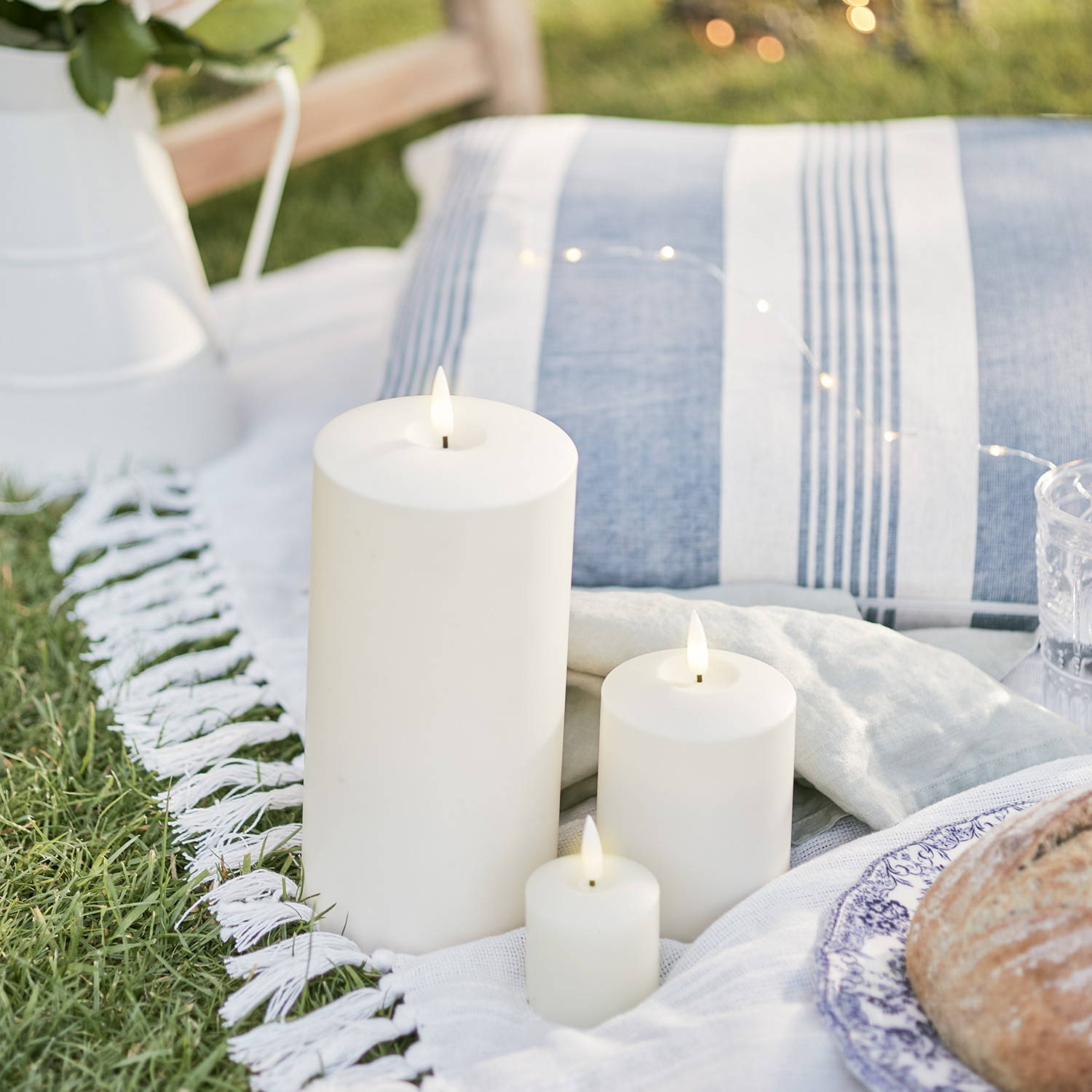 A picnic set up with 3 ivory outdoor LED candles.