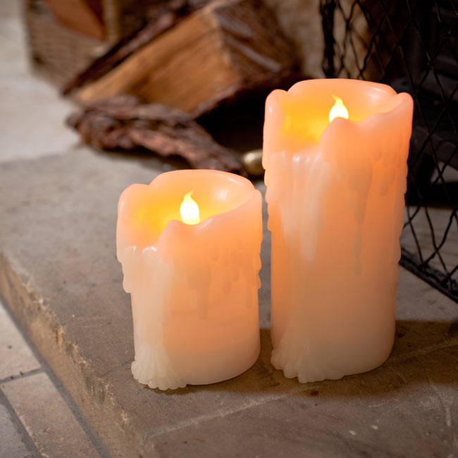 2 LED candles on a fireplace with wax running down the sides.