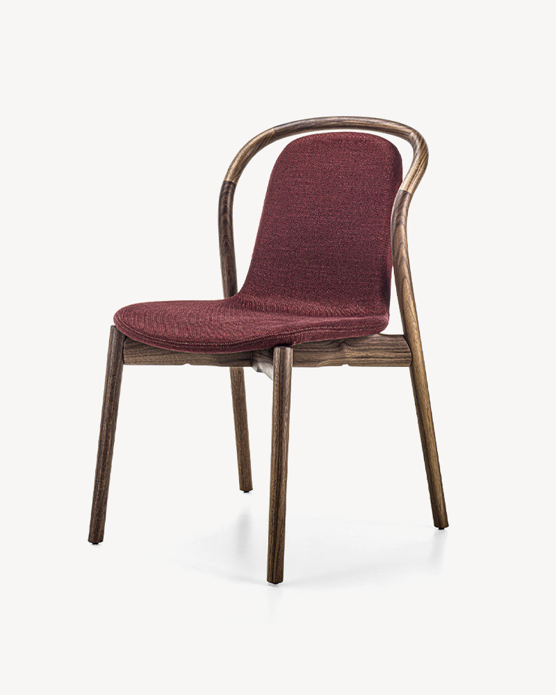 A maroon upholstered Porada chair with a wooden frame and curved backrest.