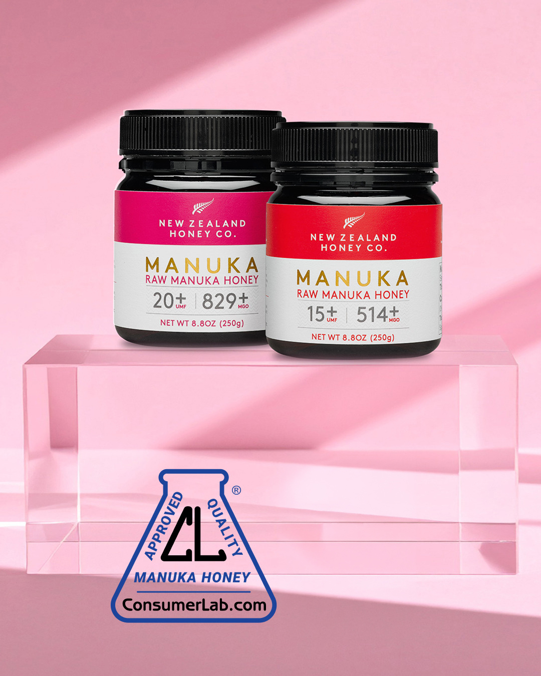 Two jars of Manuka honey on a pink background.