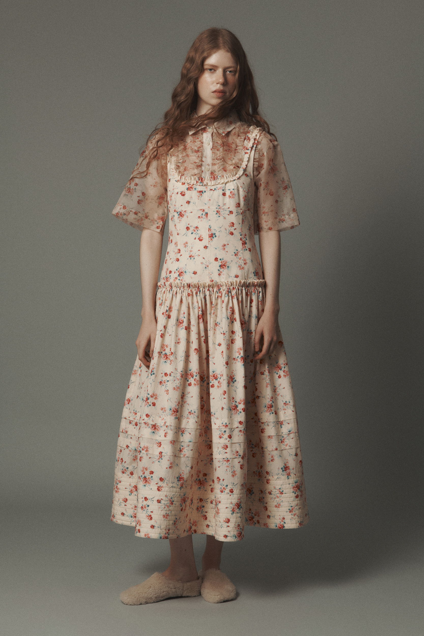 A model wearing a floral dress with puffed sleeves and a long skirt.