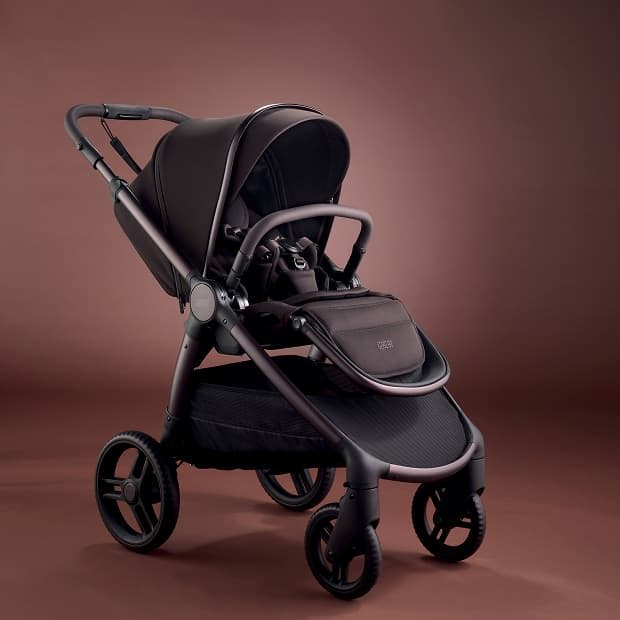 A modern black stroller on a brown background.