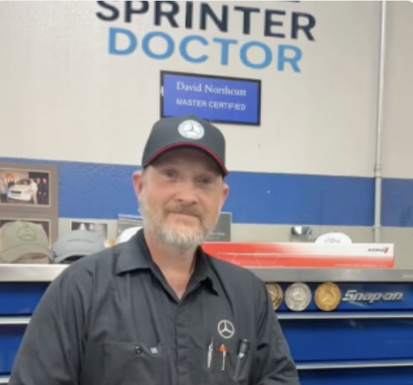 A mechanic posing in a workshop with 