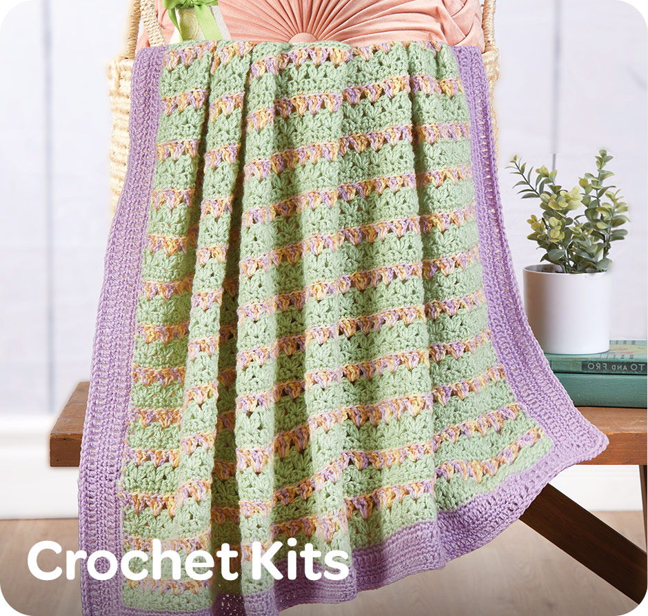 Crochet baby blanket displayed on a chair with text 