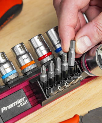 A person using a socket set with various attachments on a work surface.