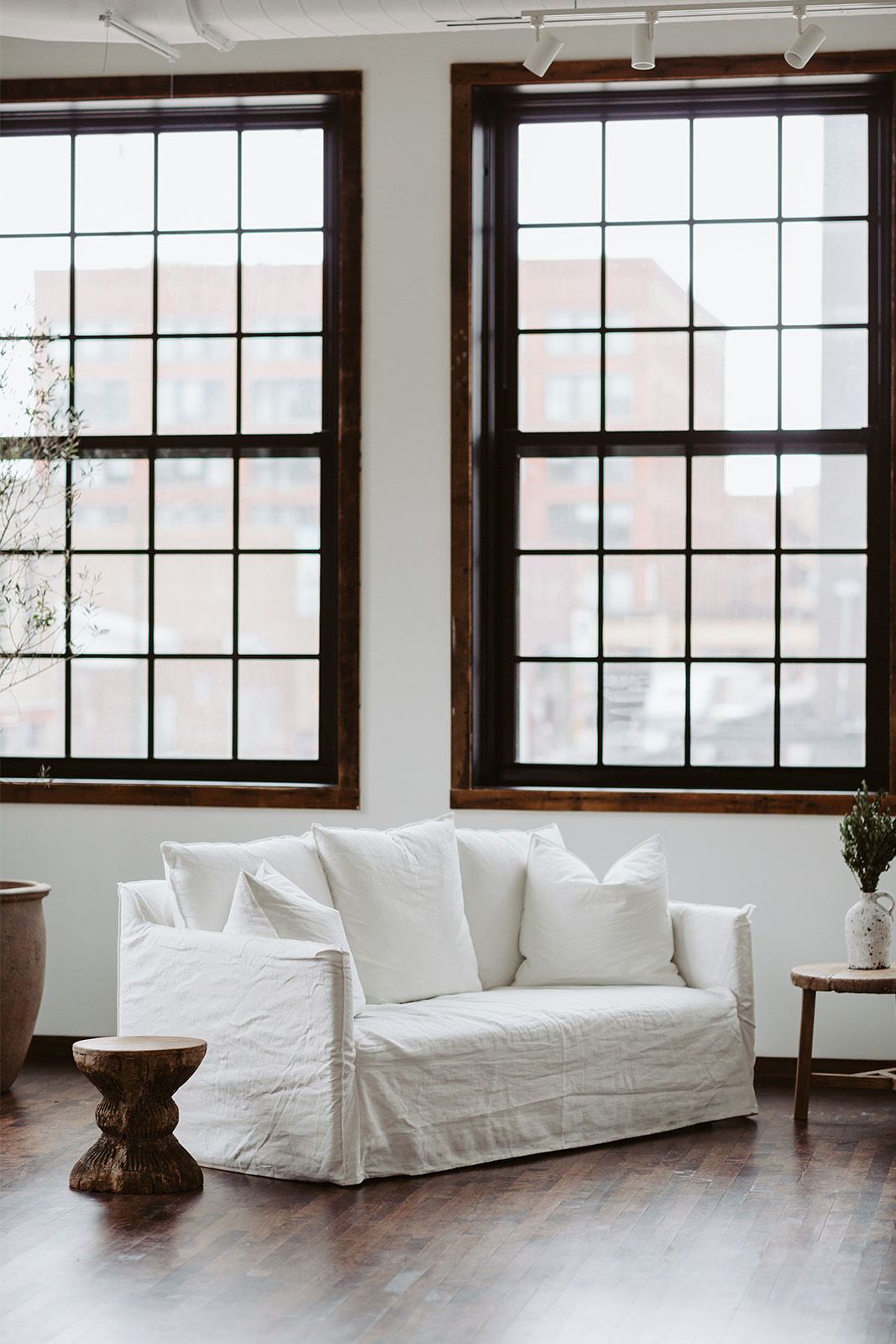 A cozy white sofa near large windows in a stylish room.