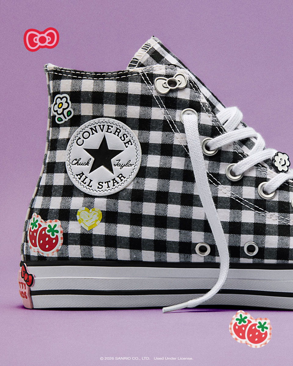 Black and white checkered Converse sneakers with colorful patches on a purple background.