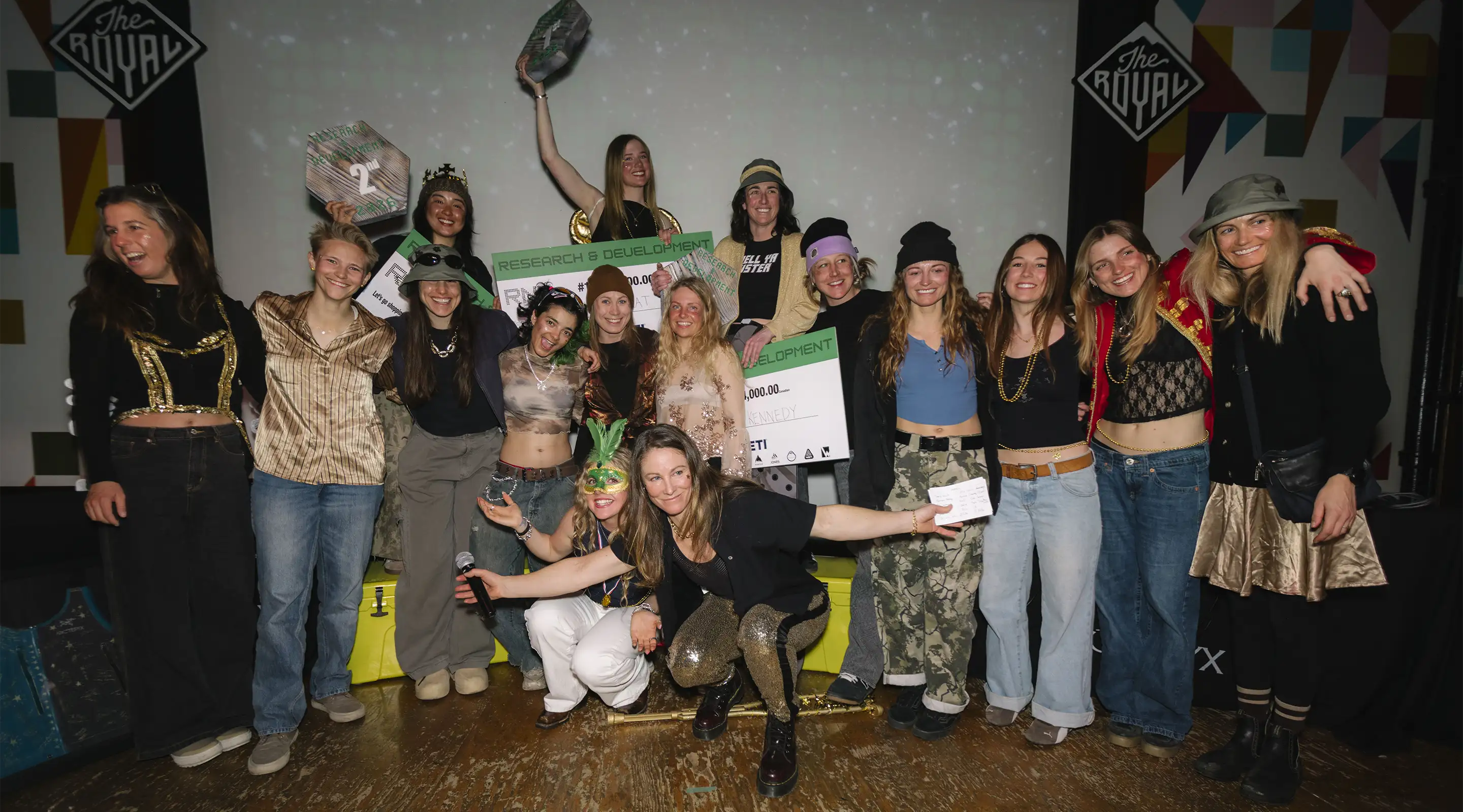 Group of people celebrating with awards and signs at an event.