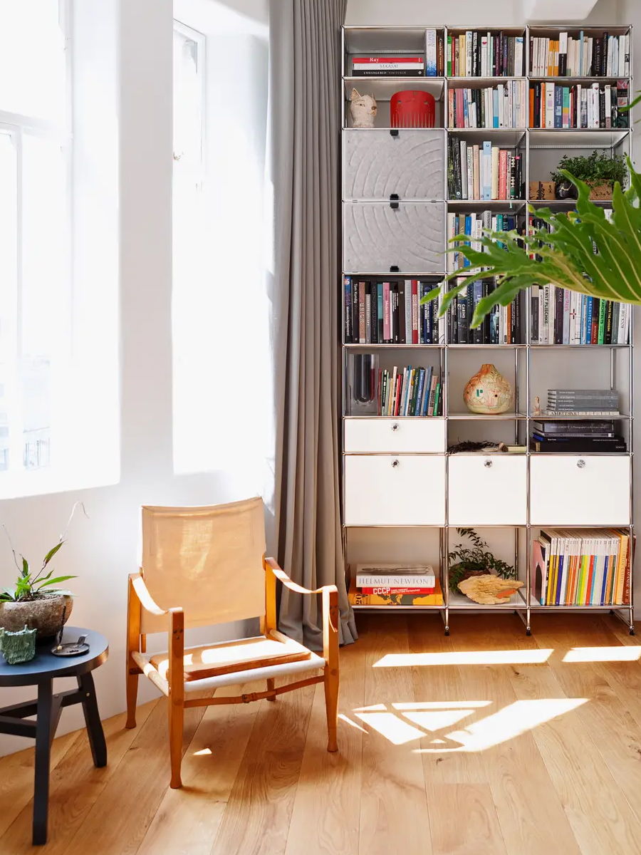 A cozy reading nook with a chair, bookshelf, and potted plant.