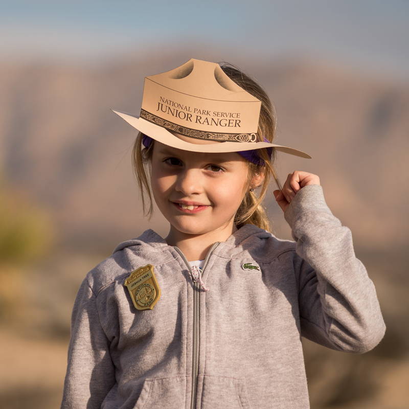 Young girl with junior ranger hat and badge on.