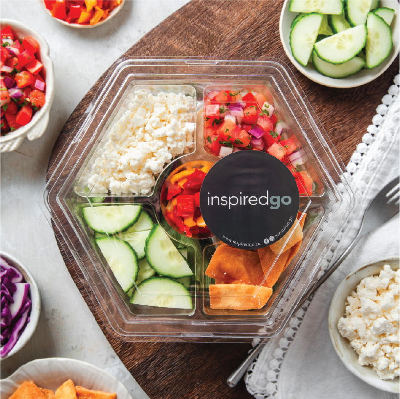 Hexagonal salad container with assorted vegetables and toppings.