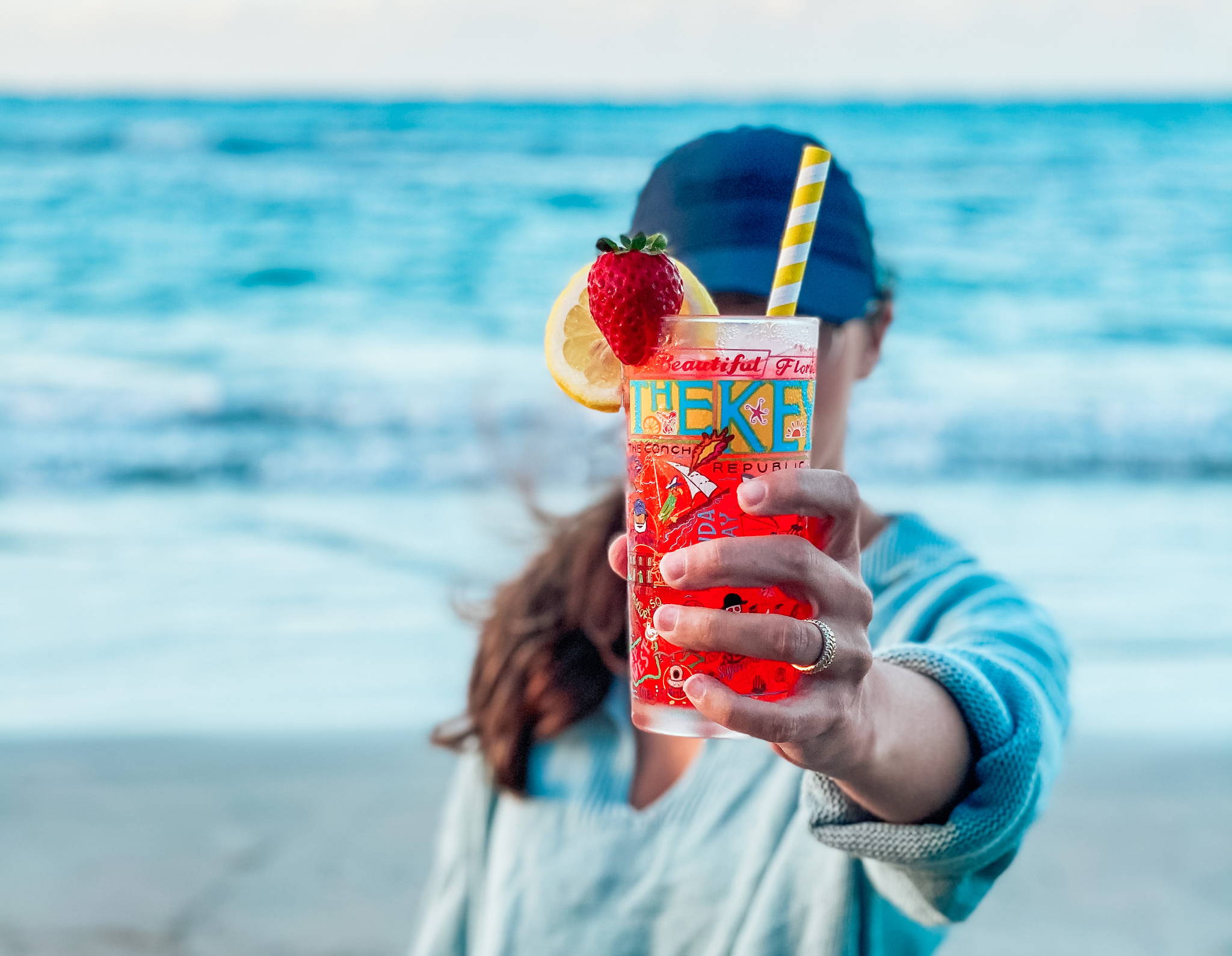 Woman holding Florida Keys glass with juice on a beach