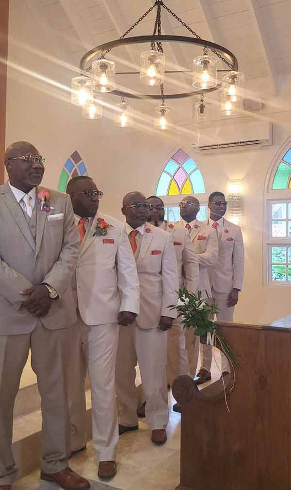 Groomsmen inside a wedding chapel wearing burnt orange ties and pocket squares