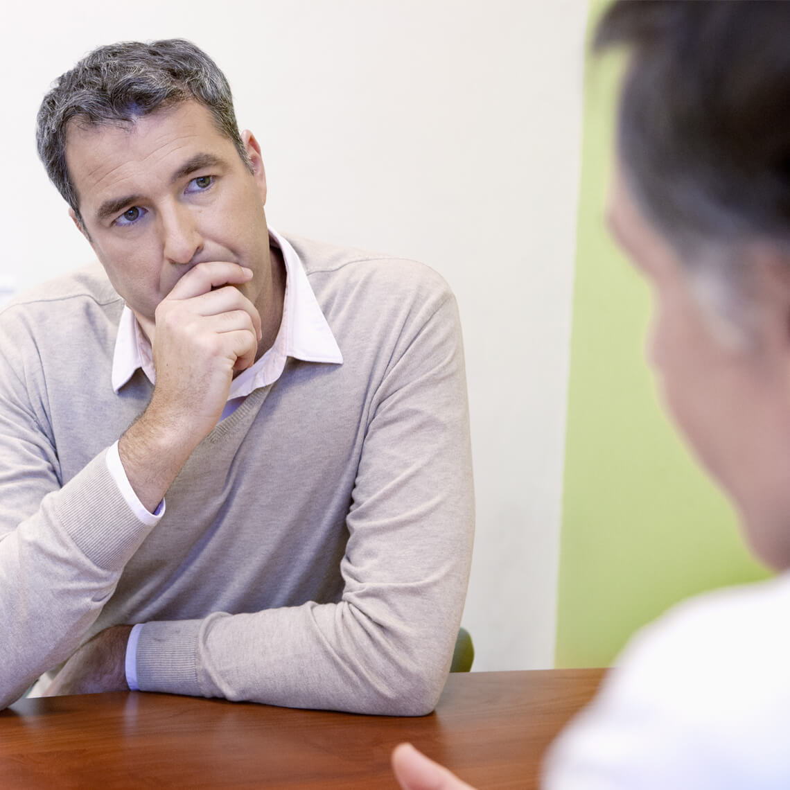 Two men engaged in a serious conversation at a table.