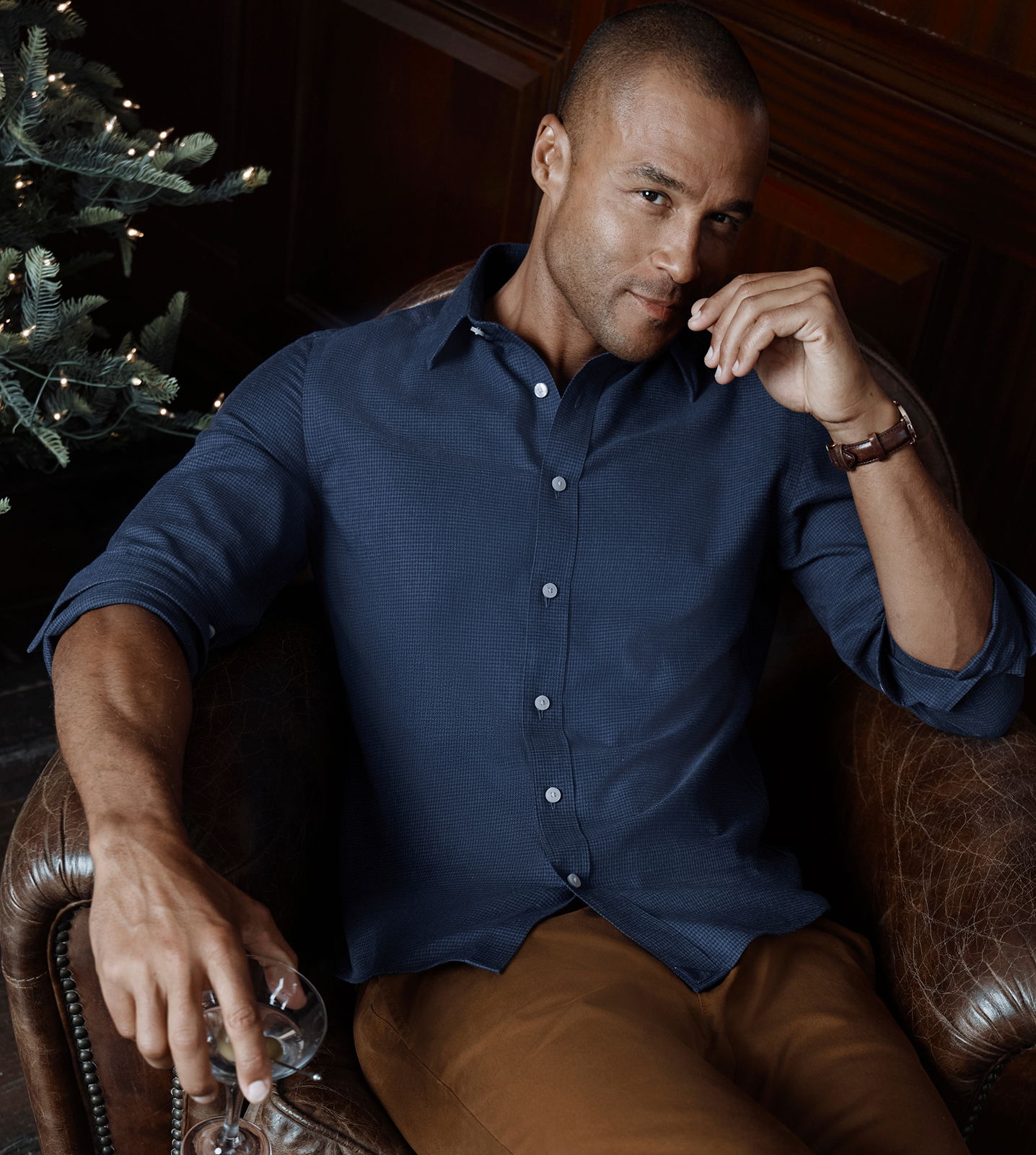Man sitting in a chair, wearing a navy shirt, relaxed expression.